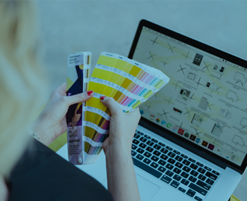 lady sitting with laptop and looking through colour swatches in her hands