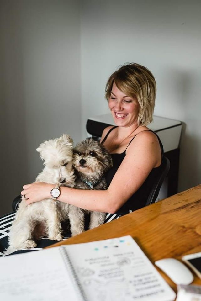 lauren sitting in chair grinning and holding two dogs