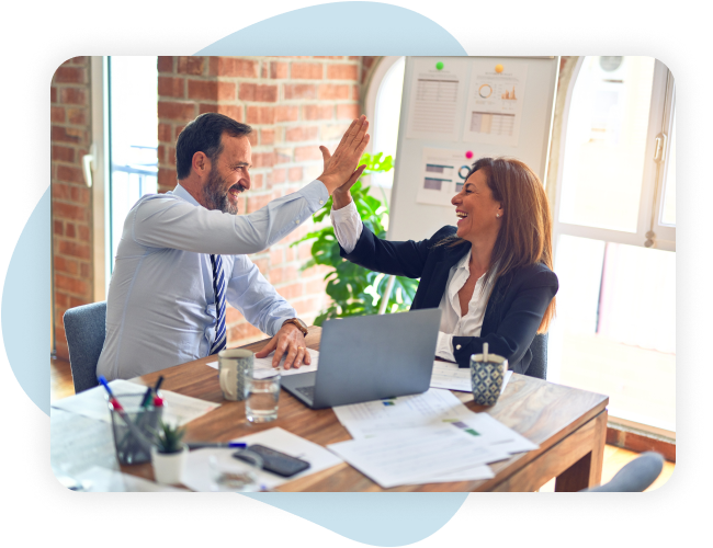 professional man and woman high-fiving at a work desk